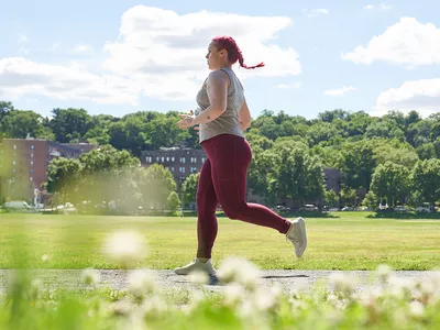 woman running on a path with buildings in the background