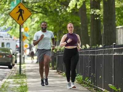 man and woman running on a city street