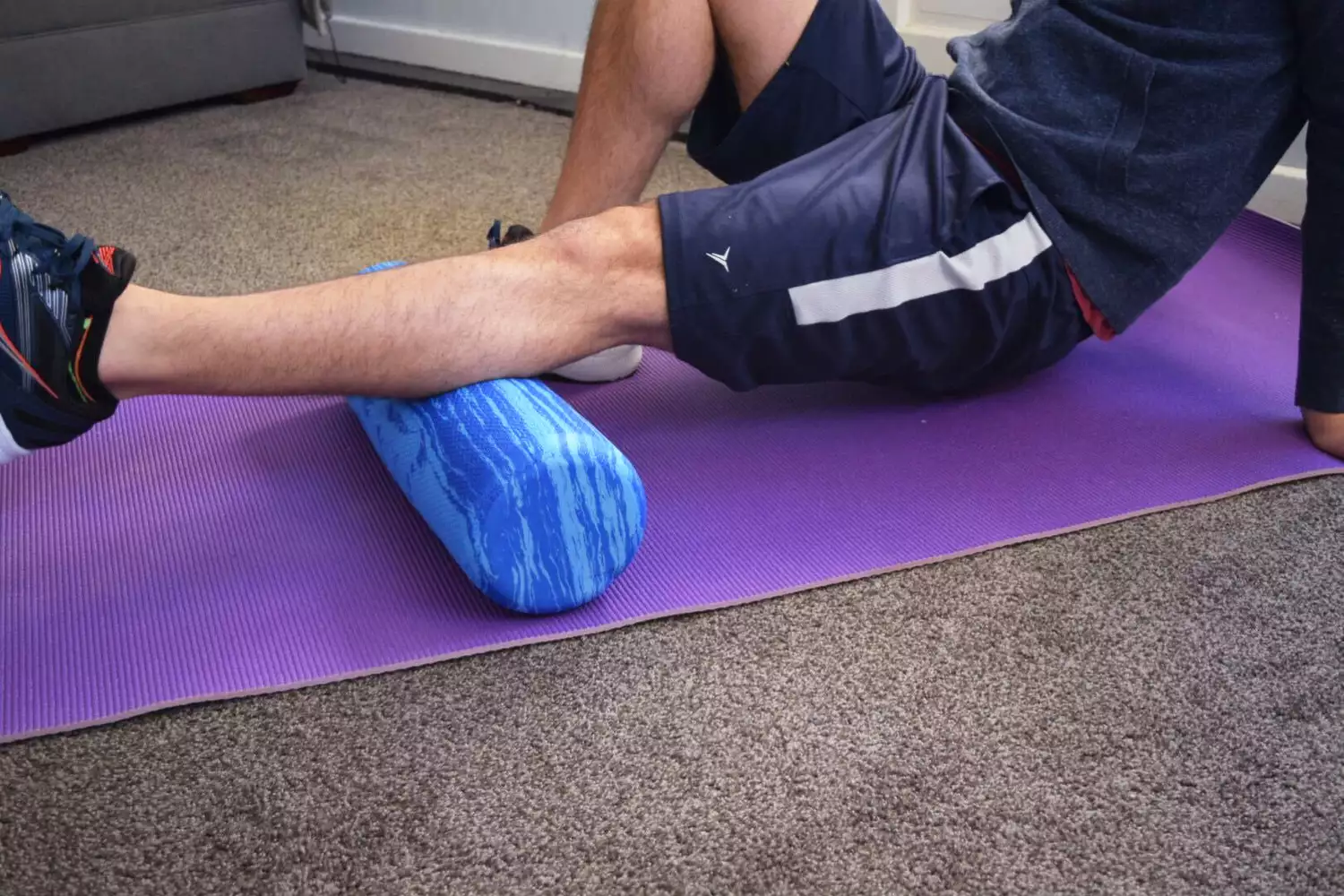 Person placed leg on OPTP Pro Soft Roller while sitting on yoga mat