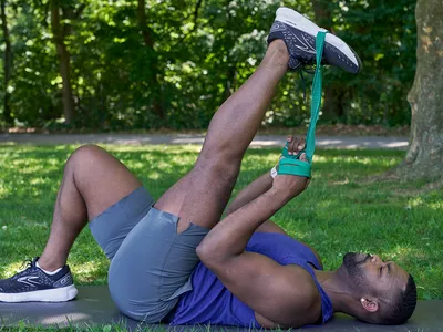 man using a resistance band to stretch leg