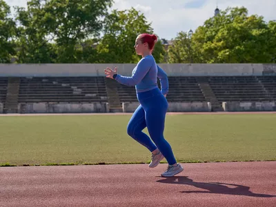 woman in all blue running on a track