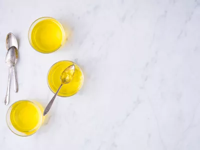 Jello in cups with metal spoons on a countertop.