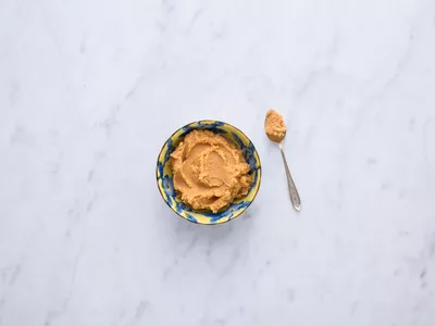 Miso in a yellow and blue bowl with a spoon.