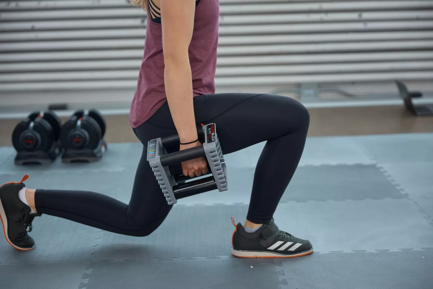 A person does lunges while holding the POWERBLOCK Elite EXP Adjustable Dumbbell