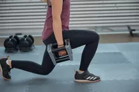 A person does lunges while holding the POWERBLOCK Elite EXP Adjustable Dumbbell