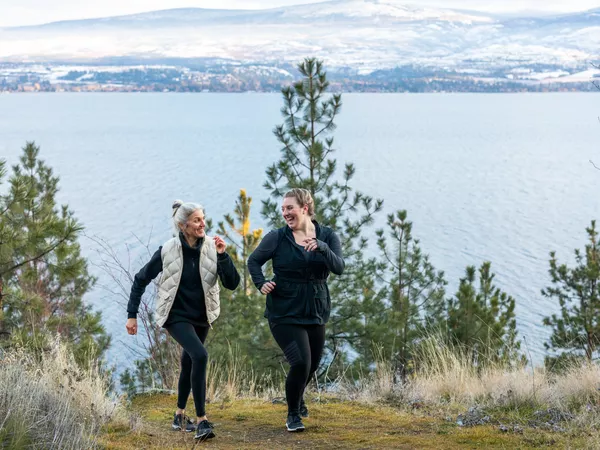 two women walking together on a coastal mountain trail