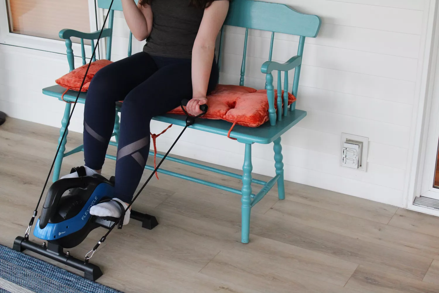 Person exercising using LifePro FlexCycle Exercise Bike Under Desk Bike Pedal Exerciser while sitting on bench