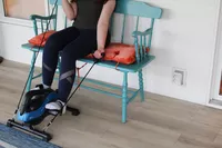 Person exercising using LifePro FlexCycle Exercise Bike Under Desk Bike Pedal Exerciser while sitting on bench