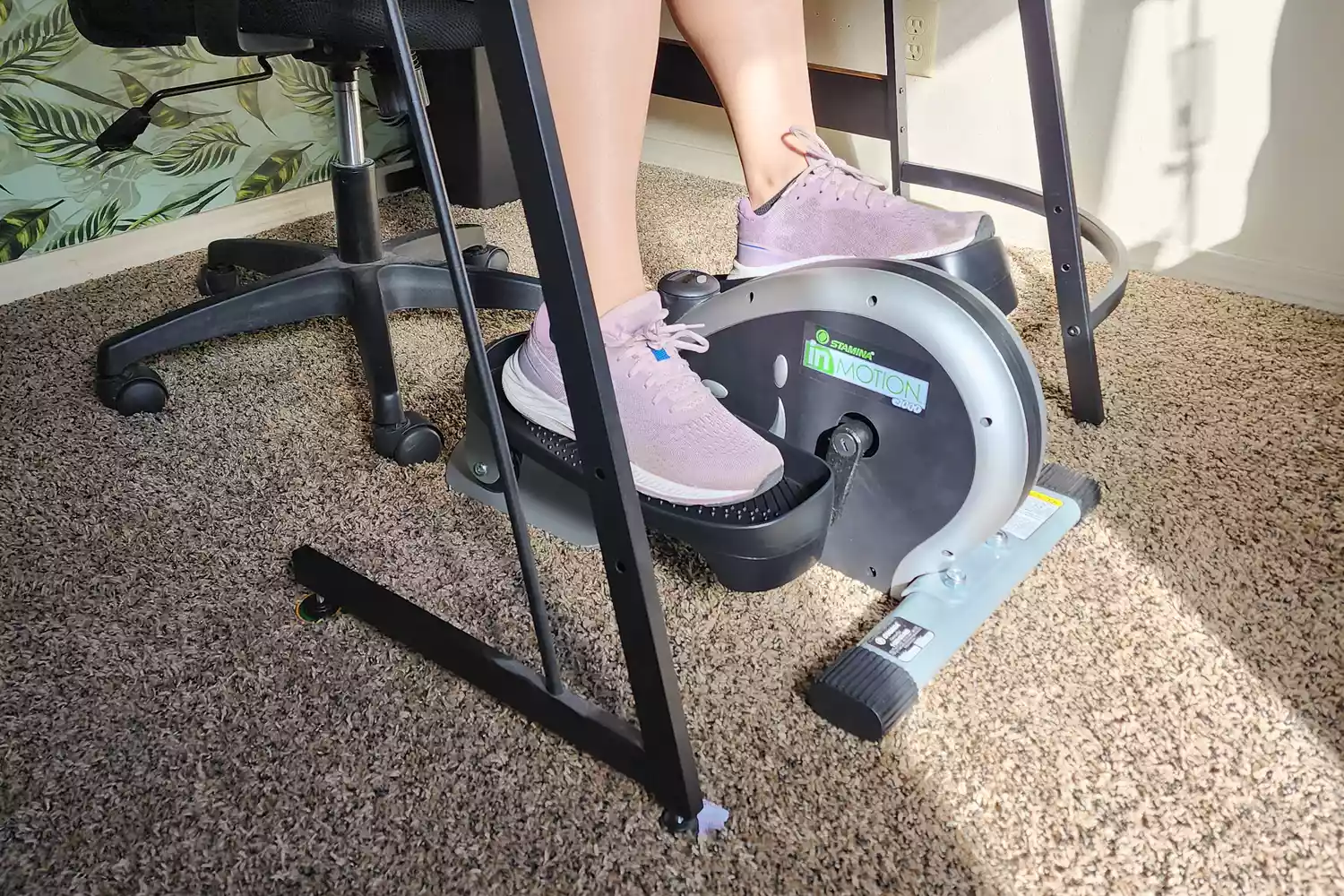 Closeup of a person using the Stamina InMotion E1000 Compact Strider while sitting at a desk