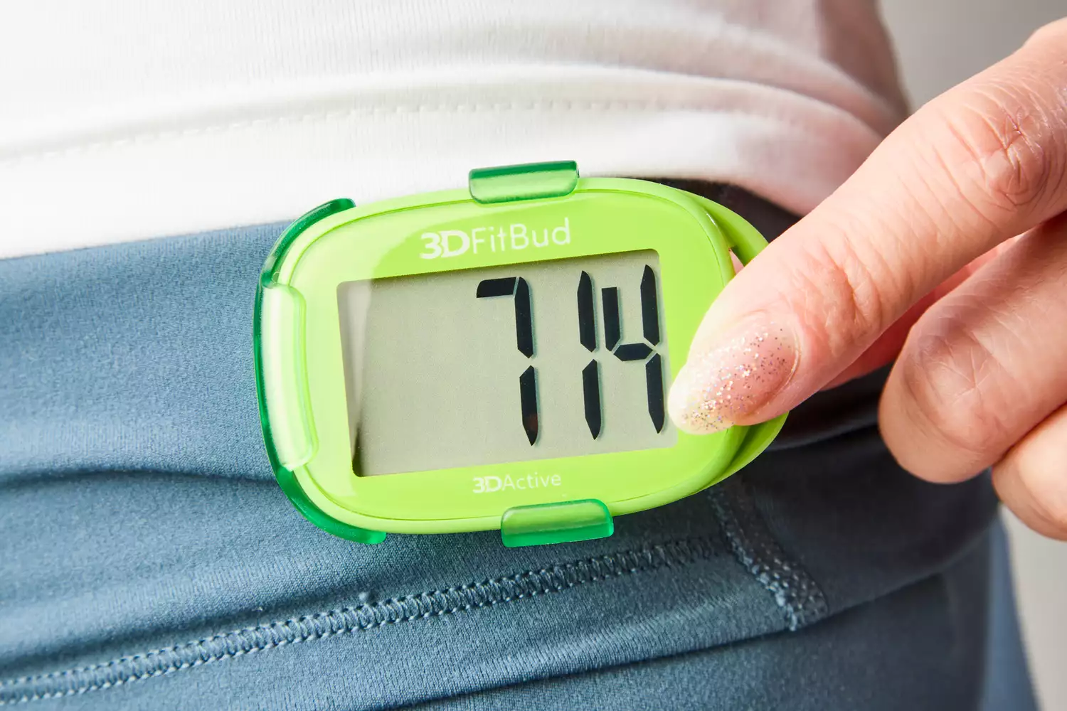 A person touches the 3DActive 3DFitBud Simple Step Counter 3D Pedometer clipped to their waist