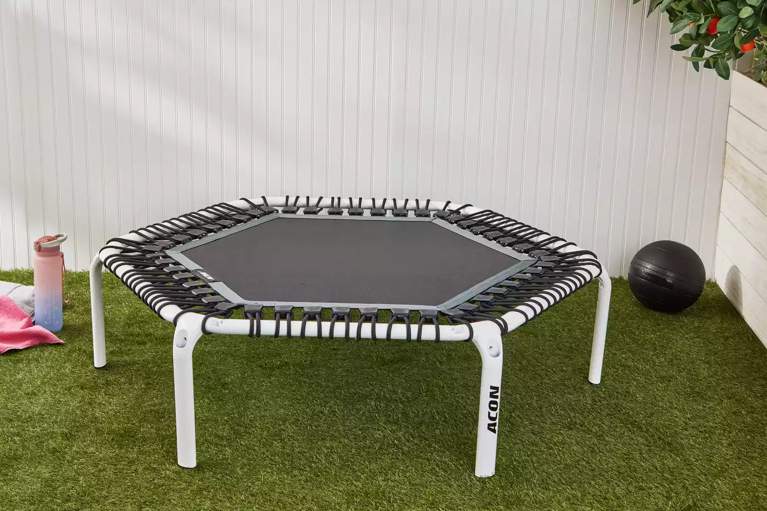 Acon 55in Trampoline Hexagon displayed on a lawn next to a water bottle and ball