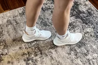 A close-up of two legs wering the Adidas Women's Ultraboost 1.0 Shoes on a rug