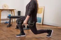 A person does lunges while holding the All in Motion 25 lb Adjustable Dumbbell