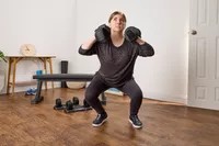 A person squats while holding the All in Motion 25 lb Adjustable Dumbbells