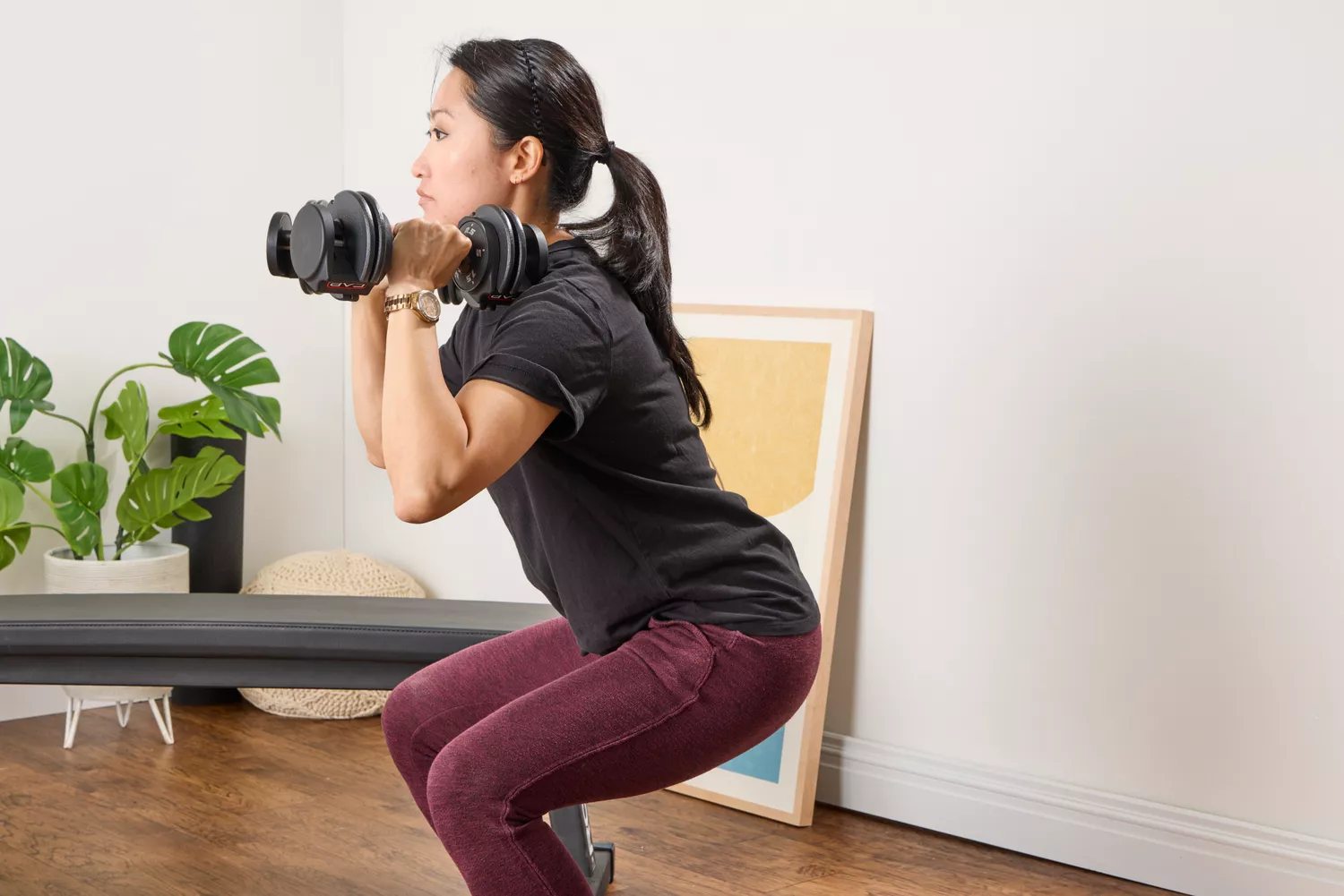 A person squats while holding the CAP Barbell 25 lb. Adjustable Dumbbells