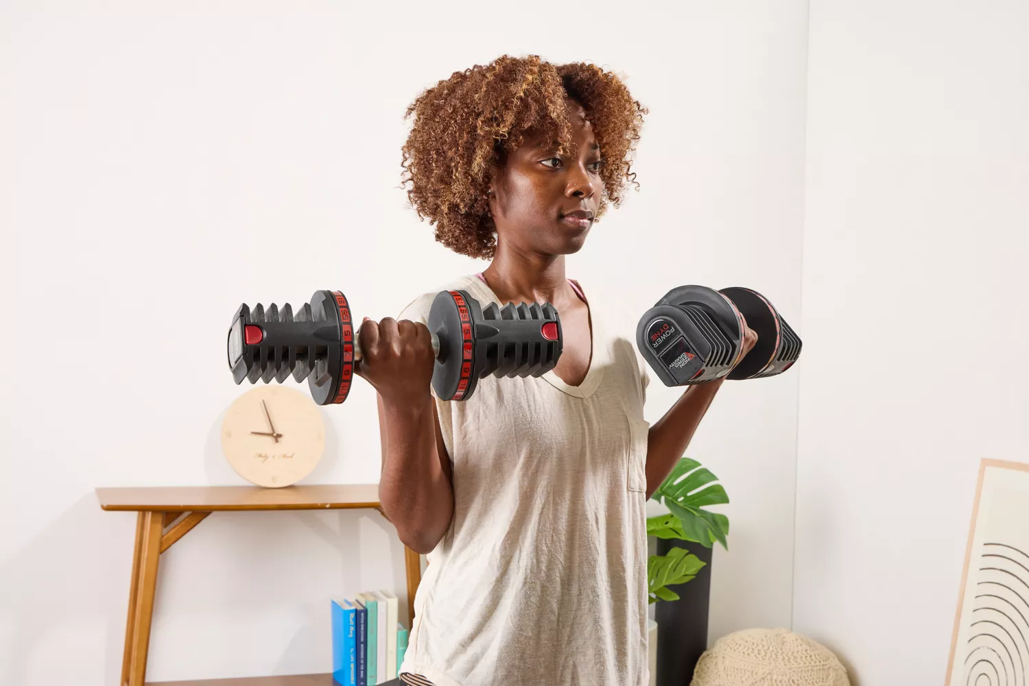 A person lifts the Non Zero Gravity 55 lbs PowerDyne Adjustable Dumbbells while exercising