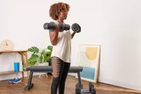 A person lifts the Non Zero Gravity 55 lbs PowerDyne Adjustable Dumbbells