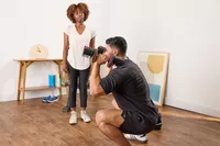 A person squats while holding the Non Zero Gravity 55 lbs PowerDyne Adjustable Dumbbells