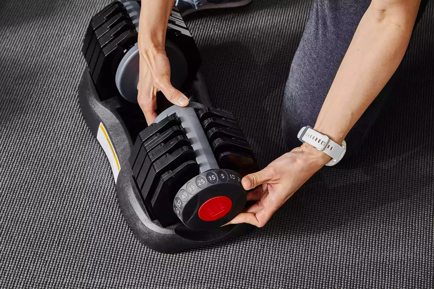 Hand adjusting the weight on the ETHOS 50 lb. Selectable Dumbbell