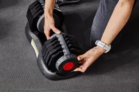 Hand adjusting the weight on the ETHOS 50 lb. Selectable Dumbbell