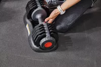 Hand holding ETHOS 50 lb. Selectable Dumbbell