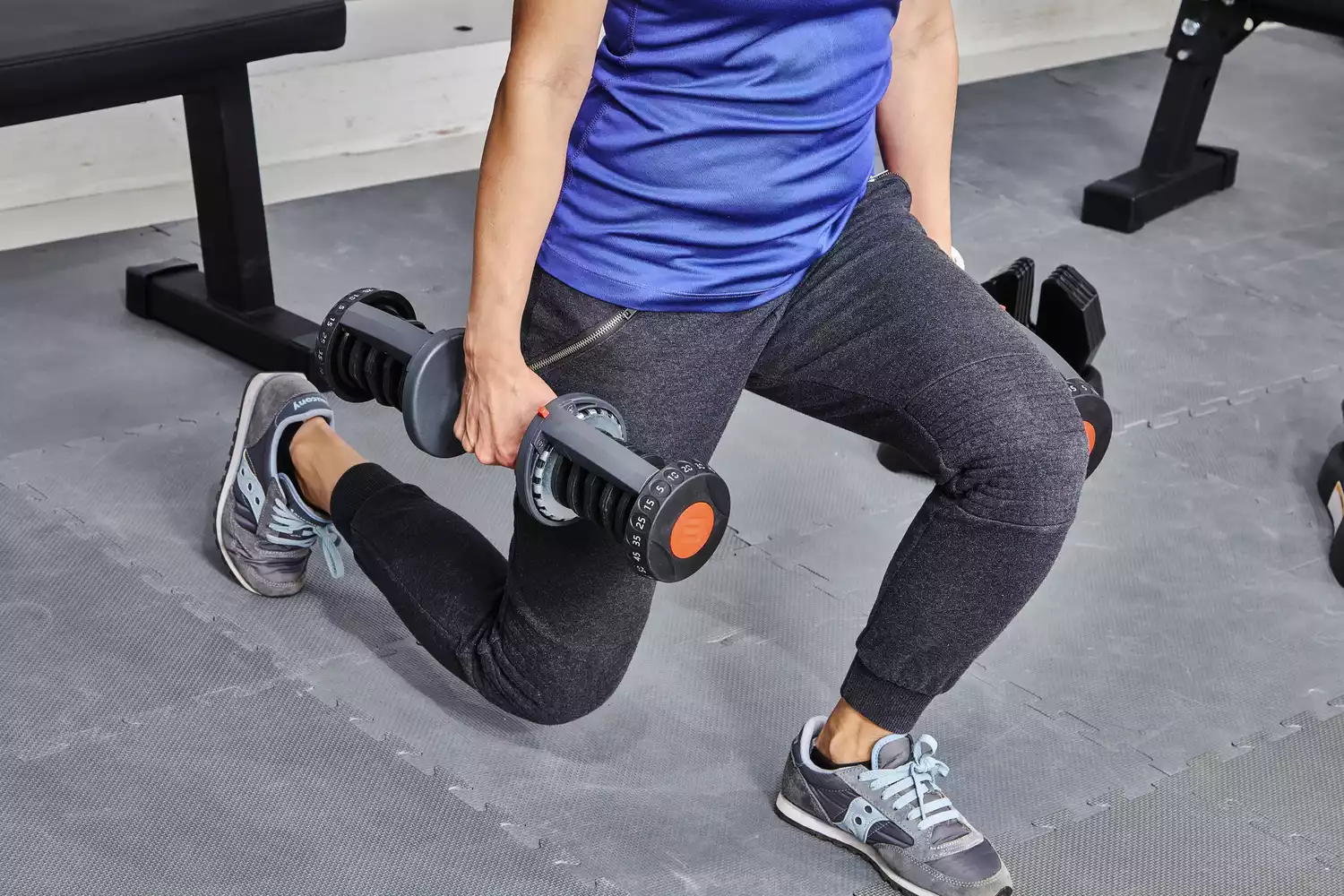 Person performing a lunge with the ETHOS 50 lb. Selectable Dumbbells