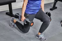 Person performing a lunge with the ETHOS 50 lb. Selectable Dumbbells