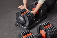 Hand holding FitRx SmartBells Set Quick Select Adjustable Dumbbells