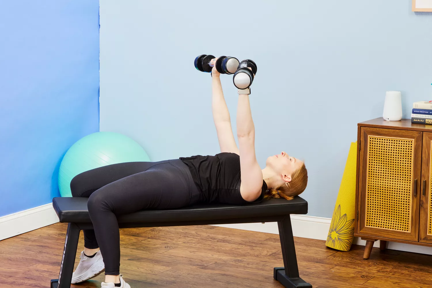 A person does chest presses using the Lifepro PowerFlow Plus Adjustable Dumbbell Set