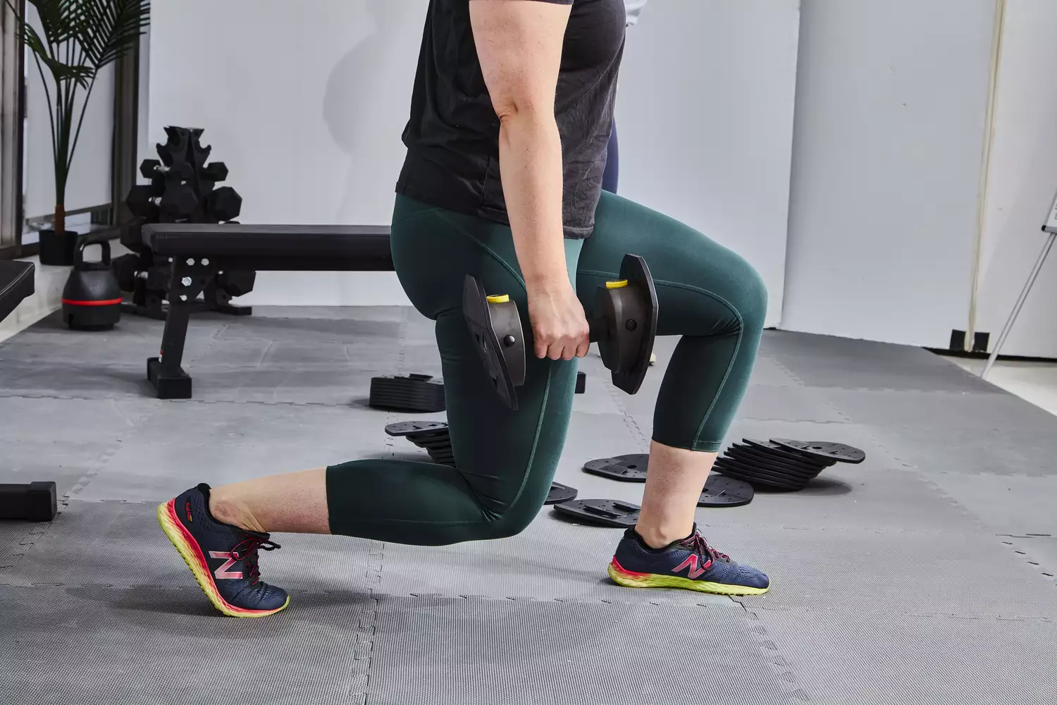 Person lifting MX55 Rapid Change Adjustable Dumbbells while performing a lunge