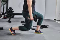 Person lifting MX55 Rapid Change Adjustable Dumbbells while performing a lunge
