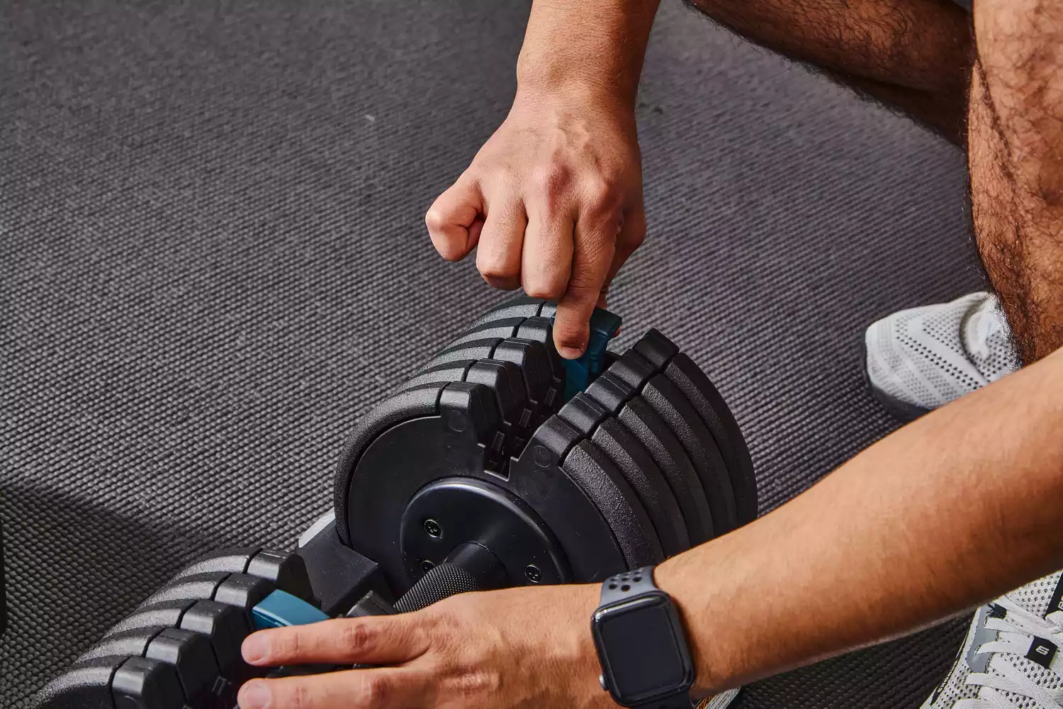 Hand adding weight to ProForm Select-a-Weight Adjustable Dumbbells