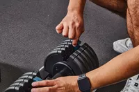 Hand adding weight to ProForm Select-a-Weight Adjustable Dumbbells