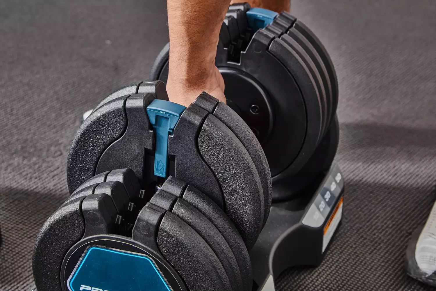 Hand preparing to pick up the ProForm Select-a-Weight Adjustable Dumbbells