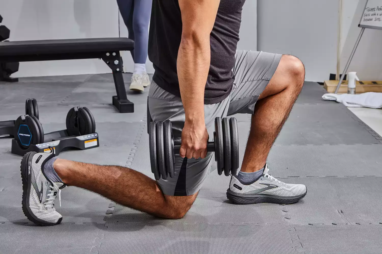Person doing a lunge with the ProForm Select-a-Weight Dumbbells