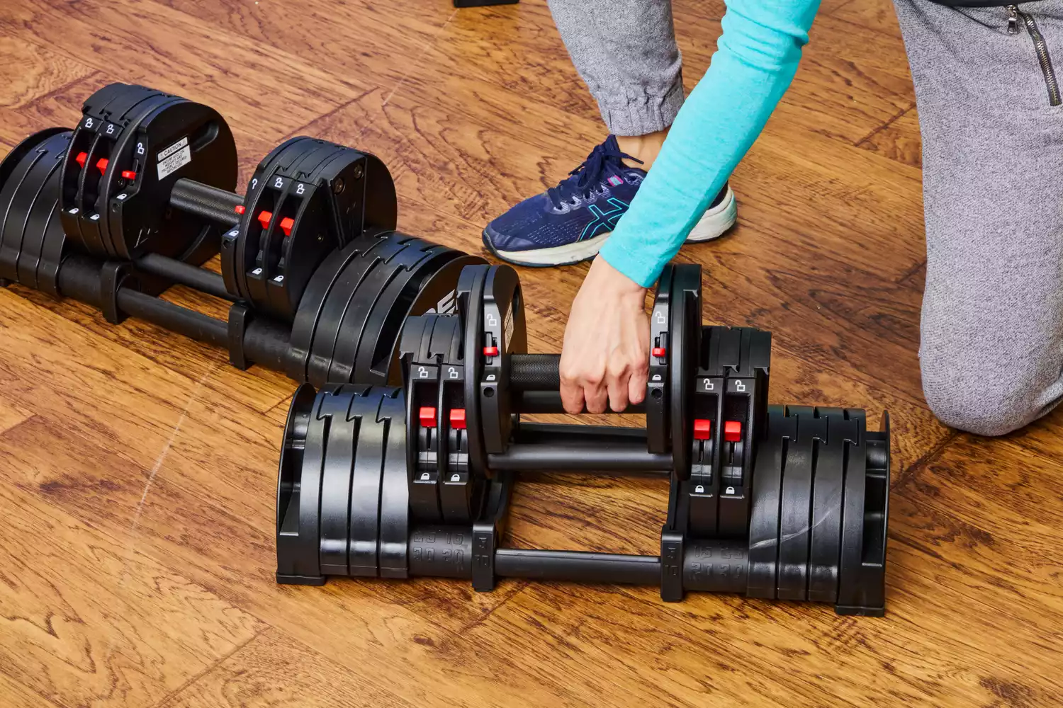 A person lifts the weight bar from the Rep Fitness Quickdraw Adjustable Dumbbell out of the base