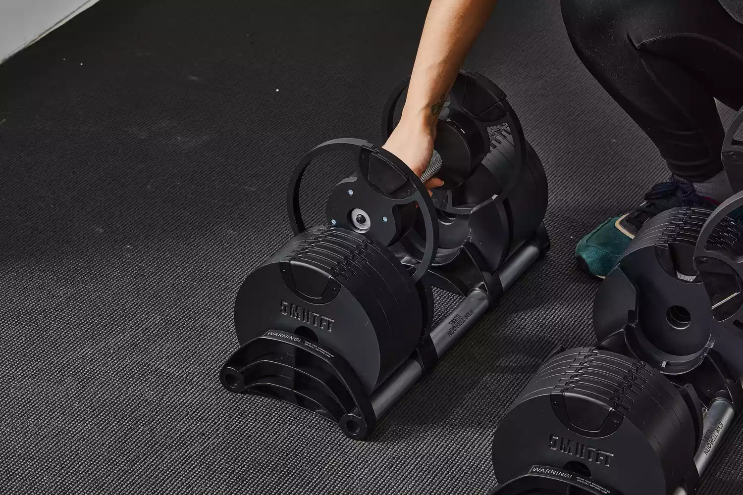 Hand positioned to pick up a Nuobell Adjustable Dumbbell