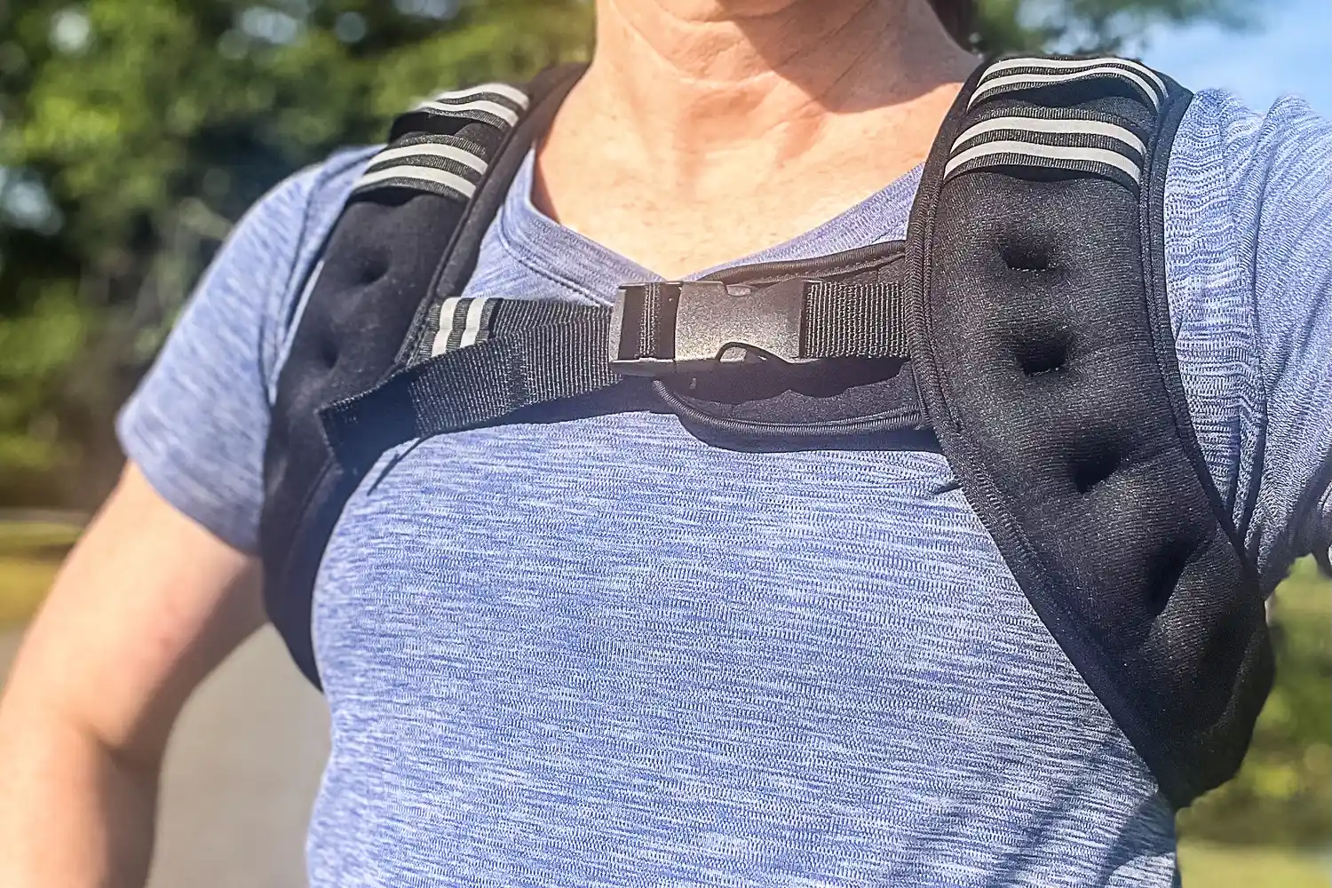A person wearing a blue top and Aduro Sport Adjustable Weighted Vest outdoors