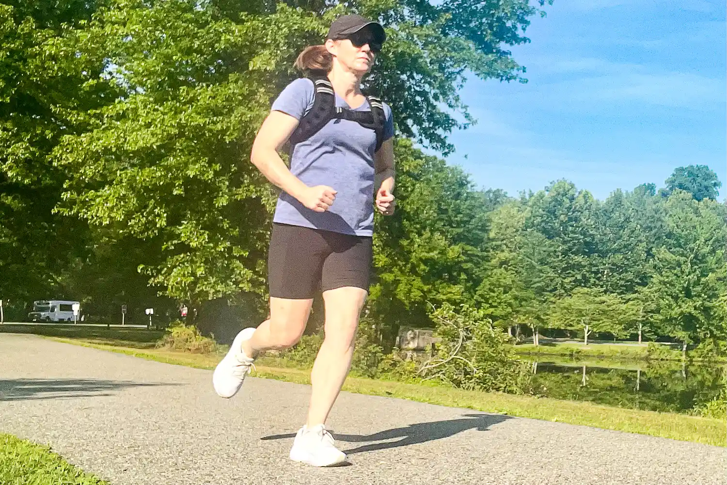 Person wearing Aduro Sport Adjustable Weighted Vest while jogging outdoors on a paved path in a park setting