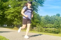 Person wearing Aduro Sport Adjustable Weighted Vest while jogging outdoors on a paved path in a park setting