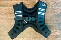 Aduro Sport Adjustable Weighted Vest with adjustable straps lying on a wooden floor