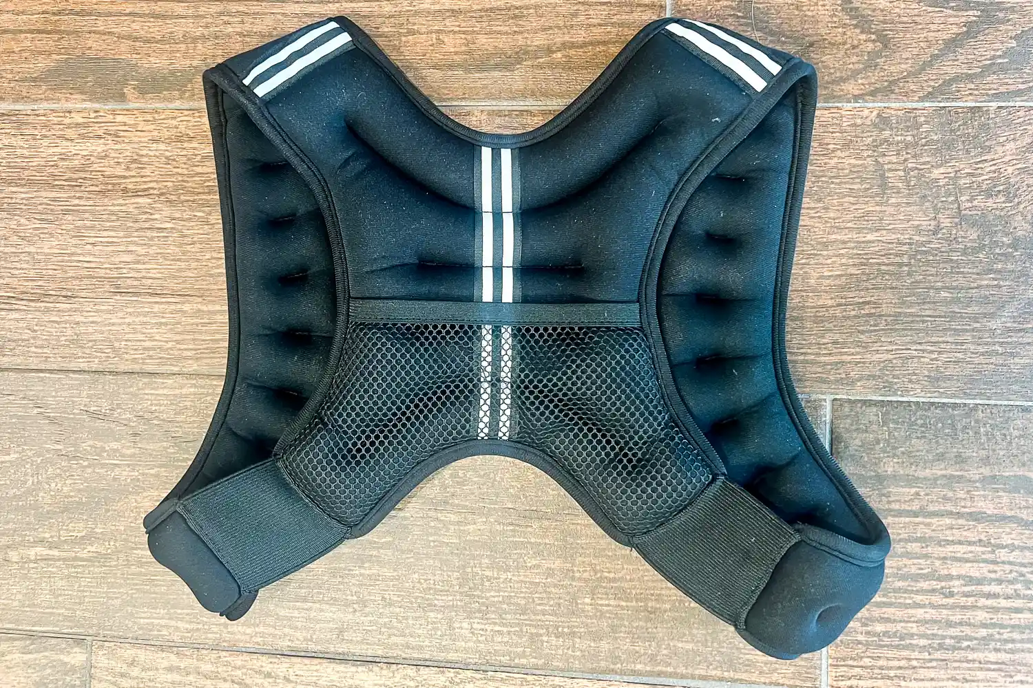 Aduro Sport Adjustable Weighted Vest for workouts shown on a wooden floor