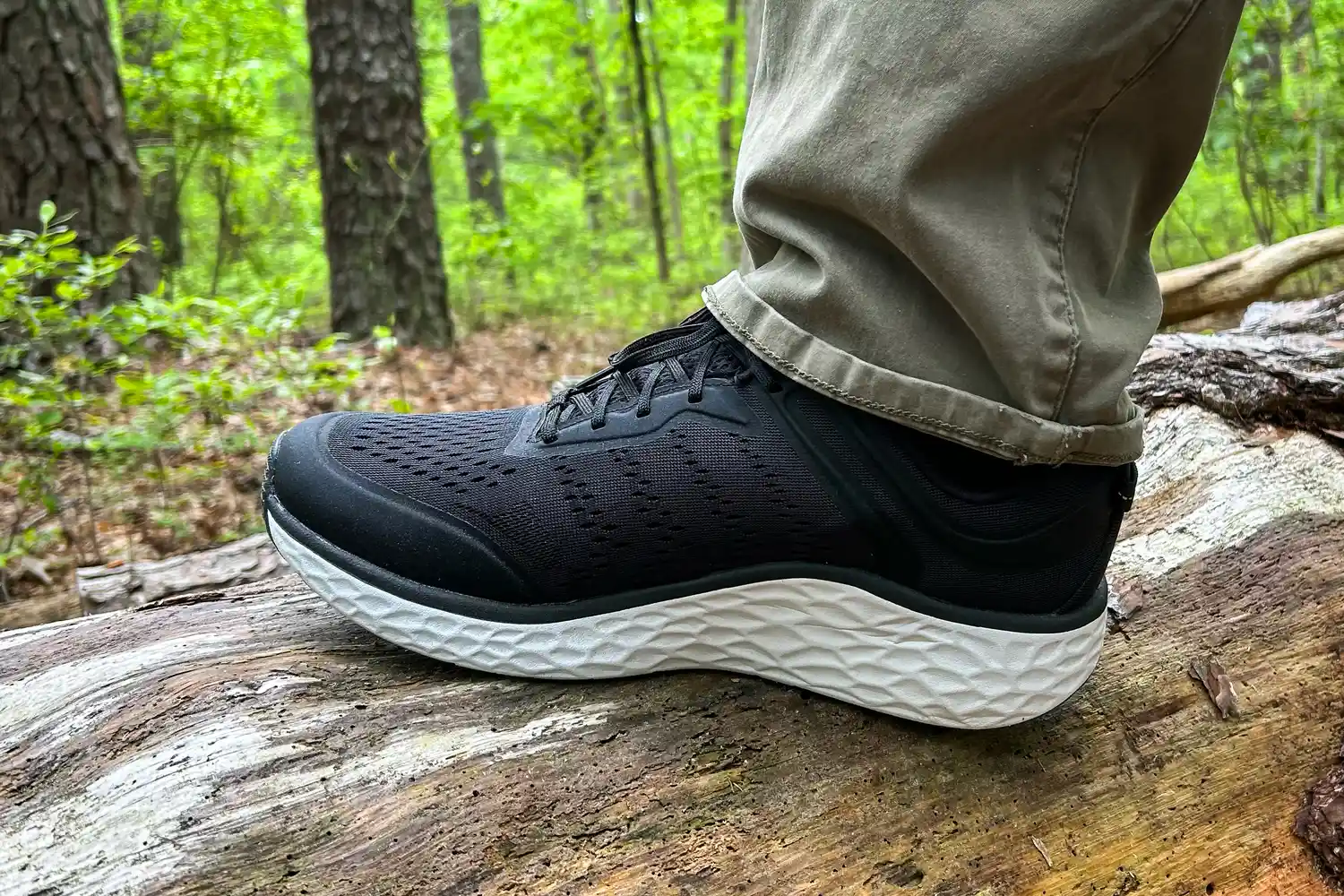 A person wearing Aetrex Chase Arch Support Sneakers standing on a fallen tree trunk in a forest