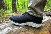 A person wearing Aetrex Chase Arch Support Sneakers standing on a fallen tree trunk in a forest