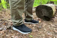 A person wearing Aetrex Chase Arch Support Sneakers standing near a log in a forest setting