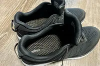 A pair of Aetrex Chase Arch Support Sneakers with insole branding visible on a wooden floor