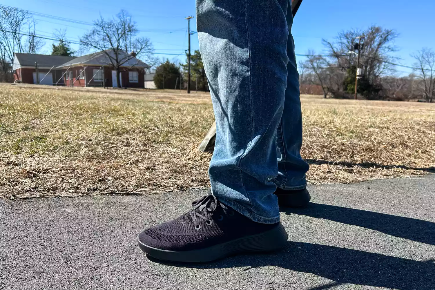 A close-up of two legs facing to the side on blacktop while wearing the Allbirds Men's Tree Runner Go