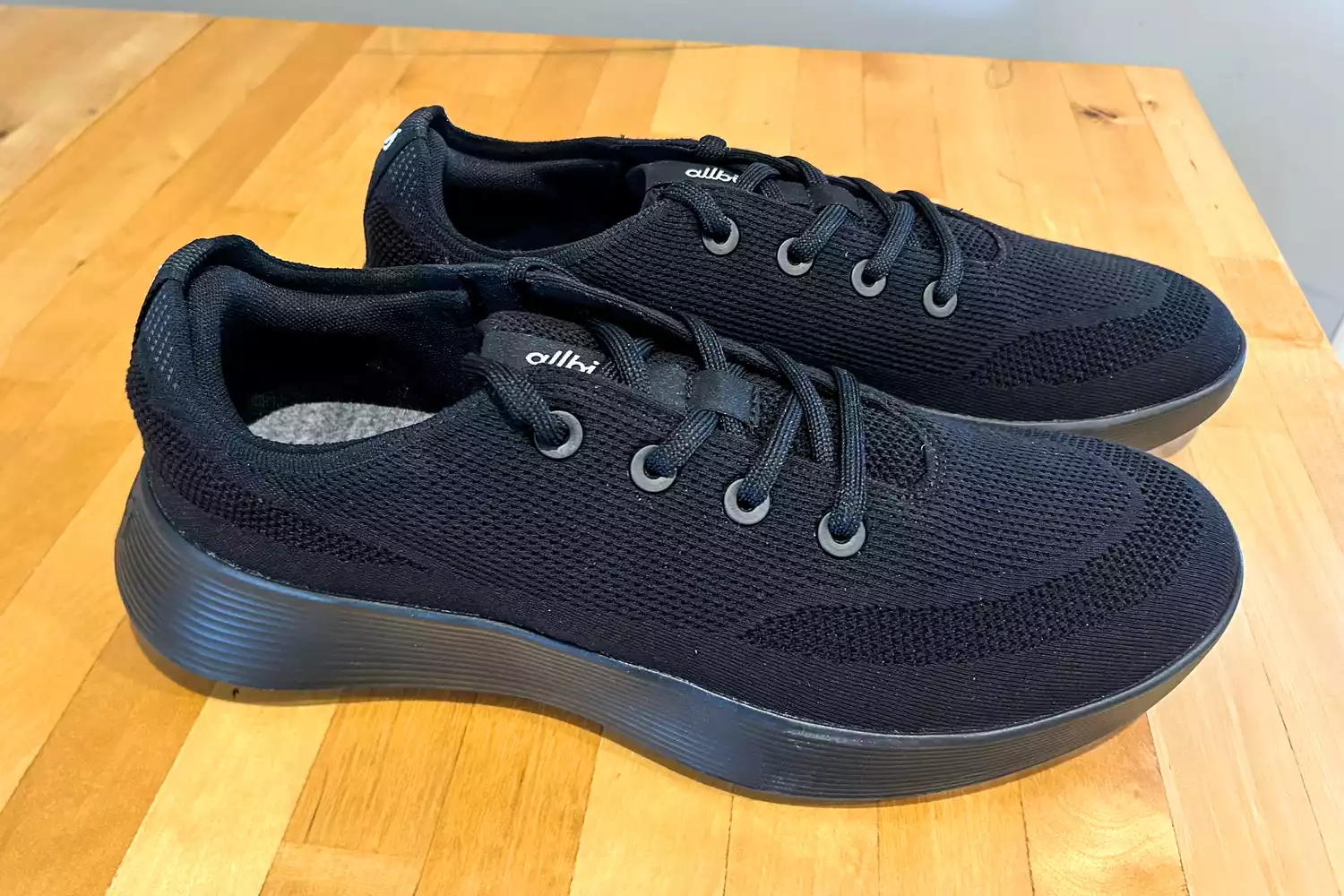 The Allbirds Men's Tree Runner Go sneakers posed on wood