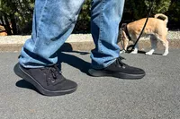 A person standing on a road while wearing the Allbirds Men's Tree Runner Go to walk their dog
