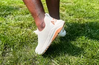 A side view of a person wearing the APL Men's TechLoom Travelers while walking through grass
